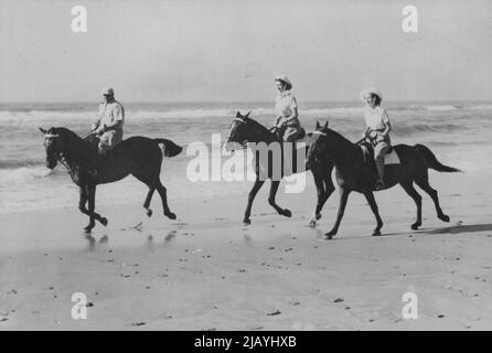 Princesses Ride On African Beach -- The Princess enjoyed an off-duty break from the Royal Tour of South Africa when they went riding on the golden sands of Bonza Beach, East London, Princess Elizabeth (centre) is riding Miss Yvonne Hayhoe's 'Jill' while Princess Margaret rides 'Treasure' owned by Mr. Pat O'Reilly. Mr. O'Reilly of East London, is seen escorting the Princesses. March 12, 1947. Stock Photo