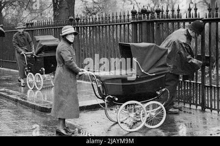 New Royal Baby Uses Her Brother's Old Pram. -- The Policeman unlocks the gate of Belgrave Square Gardens today to make way for the nurse with the pram containing Princess Alexandra (front) and Prince Edward (following). In spite of the inclement weather today the two children of the Duke and Duchess of Kent had their usual outing in Belgrave Square Gardens. Little Prince Edward has now got a new perambulator, one in which he can either sit up or lie down as he is now getting big., His old pram is being used by his sister little Princess Alexandra. February 19, 1937. (Photo by Keystone) Stock Photo