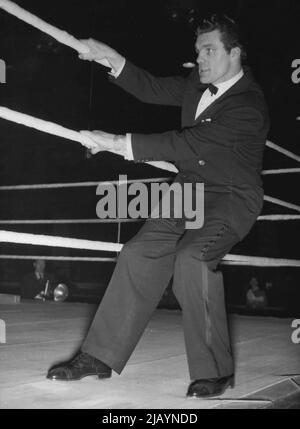 On The Outside Looking In -- Freddie, so often inside the ropes, gives them a tug from the outside to test their stretch before the contests, March 25. Freddie Mills, former world light heavyweight champion turned promoter, staged his first bill at London's Empress hall last night March 25. In the third round of the main bout Yolande Pompee, light heavyweight from Trinidad, Knocked out Danish light heavyweight champion Erik Jensen. April 24, 1952. (Photo by Rota Pictures) Stock Photo