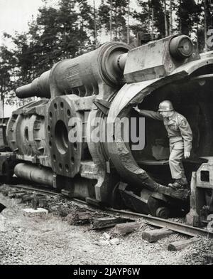 One of Hitler's biggest long-range guns will be scrapped in the near future after rusting since V-E Day at Railway siding near Grafenwoehr, Germany. This Mammoth piece, boasting two 100-foot barrels of 820mm. Each, had been held in readiness for a planned attack on Gibraltar. A similar gun was used during the siege of Sevastopol, Crimea, in the summer of 1943. Here a U.S. Army officer inspects the blown-up recoil mechanism. July 22, 1949. (Photo by Acme Photo). Stock Photo