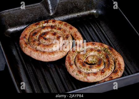 Spiral sausages on a grill pan on a dark background Stock Photo