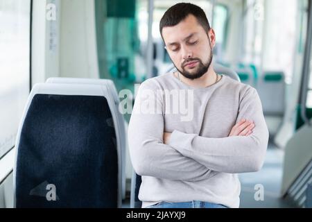Young bearded guy sleeping on seat in tram Stock Photo