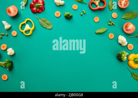 Various fresh vegetables such as tomato, broccoli, peas, bell pepper and leaves on green background Stock Photo