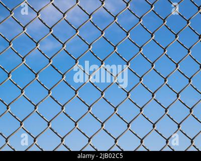 Fence with metal grid in perspective. Metal fence Part of a metal grid fence in blue sky at the background. Street view, depth of field, nobody Stock Photo