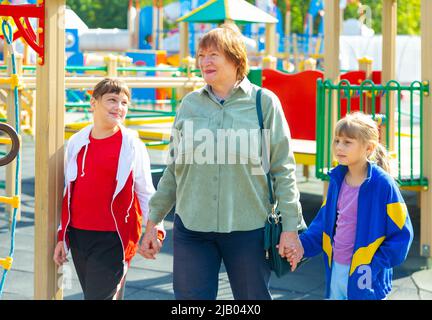 Grandmother walks with her grandchildren on playground Stock Photo