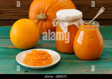 Homemade sweet pumpkin jam in white plate and in glass jars with whole pumpkin and orange horizontal Stock Photo
