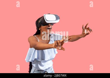 Excited young black lady in VR glasses interacting with cyberspace, playing online game in virtual reality Stock Photo