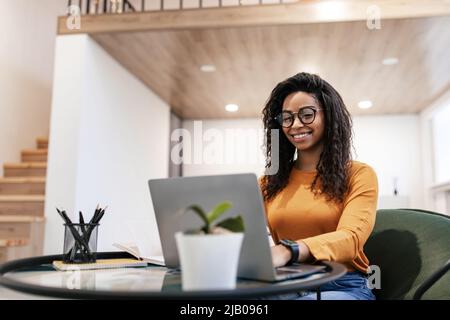 Portrait of smiling black woman using laptop at home Stock Photo