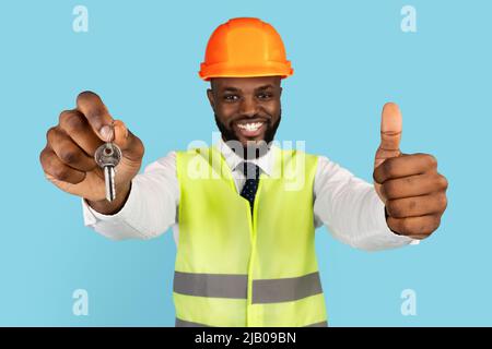 Happy Black Property Developer Wearing Hardhat Showing Home Keys And Thumb Up Stock Photo