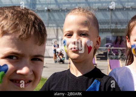 June 1, 2022, Krakow, Malopolskie, Poland: Ukrainian refugee children seen with Ukrainian and Polish national colours painted on their chicks during the Children's Day. The outdoor games are organised in both Polish and Ukrainian languages by PKP Intercity transport company. As more than 3.5 million people have fled Ukraine for Poland, the country looks for ways to integrate and accommodate newcomers. The Polish population welcomed the refugees, and many NGOs provide humanitarian help. (Credit Image: © Dominika Zarzycka/SOPA Images via ZUMA Press Wire) Stock Photo