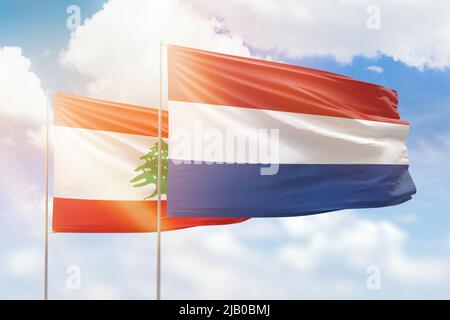 Sunny blue sky and flags of netherlands and lebanon Stock Photo