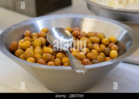 Closeup of marinated green olives in bowl on table Stock Photo