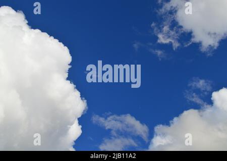The sun shines through a blue sky with white clouds Stock Photo
