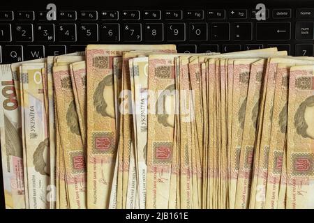 Ukrainian one hundred and two hundred hryvnia lie on the laptop keyboard, work on the Internet, income and profit, Ukrainian hryvnia Stock Photo