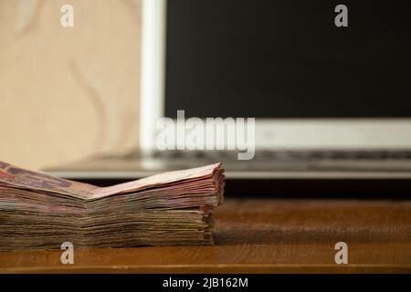 Ukrainian one hundred and two hundred hryvnias lie near a laptop on the table at home, work on the Internet, income and profit, Ukrainian hryvnias Stock Photo