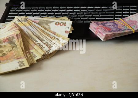 Ukrainian one hundred and two hundred hryvnia lie on the laptop keyboard, work on the Internet, income and profit, Ukrainian hryvnia Stock Photo