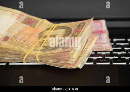 Ukrainian one hundred and two hundred hryvnia lie on the laptop keyboard, work on the Internet, income and profit, Ukrainian hryvnia Stock Photo