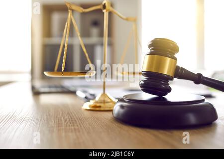 Brown judge's gavel on sound block and scales of justice on table in judge's office. Stock Photo
