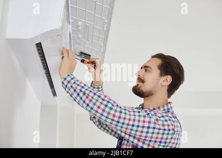 Male installer or repairman installs or repairs air conditioning inside apartment. Stock Photo