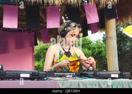 A female DJ using mixing decks with old-fashioned vinyl records outdoors Stock Photo