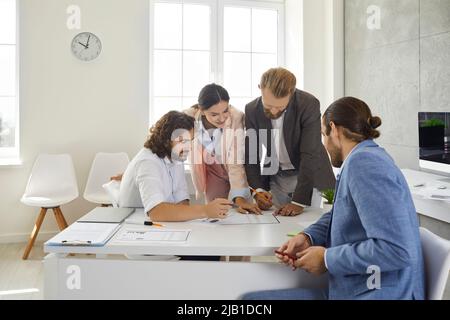 Colleagues in the office work together on a business project comparing data and analyzing lists. Stock Photo