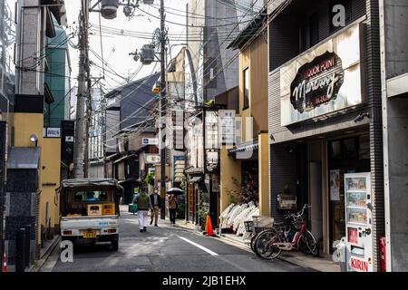 Gion, Kyoto, JAPAN - Apr 3 2021 : A back alley in Gion downtown area. There are restaurants, bars, buildings and pedestrians in image Stock Photo