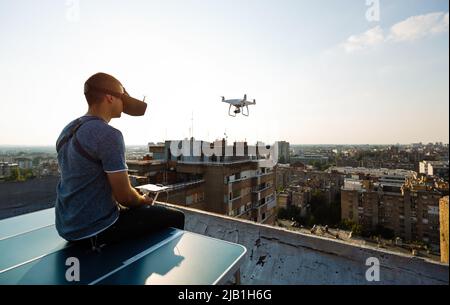 Young technician flying UAV drone with remote control on rooftop Stock Photo