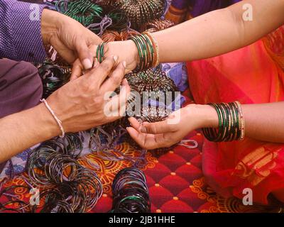 Pre wedding ceremony a lady bangle seller is putting green glass bangles, Indian culture. Stock Photo