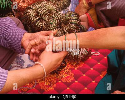 Pre wedding ceremony a lady bangle seller is putting green glass bangles, Indian culture. Stock Photo