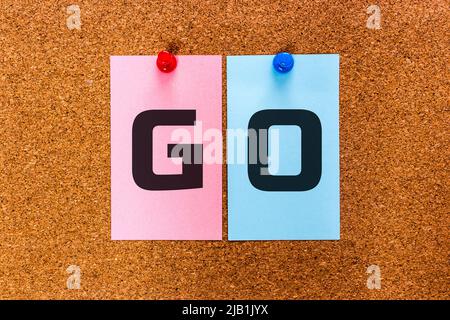Conceptual 2 letters keyword GO on multicolored stickers attached to a cork board. Stock Photo