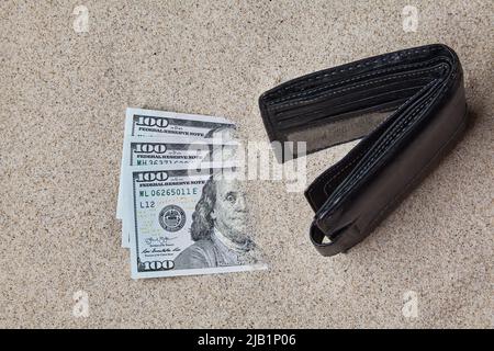 Wallet and dollars left in the sand. Lost items on the beach. Stock Photo