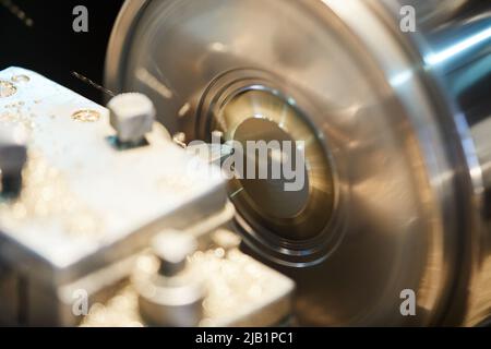 Close-up of rotating metal workpiece with cutting tool at production plant Stock Photo