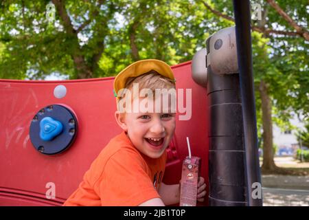 Cute little boy playing and drinking his fruit juice in the playground Stock Photo