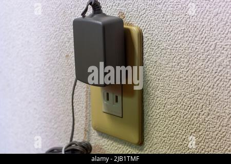 Closeup an old A-type AC adapter which plugged into the outlet at home. Stock Photo