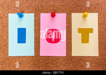 Conceptual 3 letter acronym abbreviation IoT (Internet of Things) on multicolored stickers attached to a cork board. Stock Photo