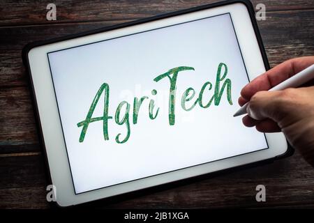 Keyword Agritech (Agricultural technology) on tablet. Concept of technology in agriculture. Man hand holding wireless stylus pen Stock Photo