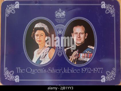 Silver Jubilee (1952-1977) celebration  British biscuit tin with portraits of Queen Elizabeth II and Prince Philip on purple background. Stock Photo