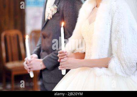 The bride, groom holds in hands wedding candle. Burn candle. Spiritual couple holding candles during wedding ceremony in christian church. close up. Stock Photo