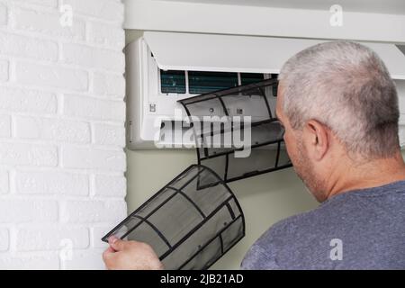 Male technician cleaning air conditioner indoors Stock Photo