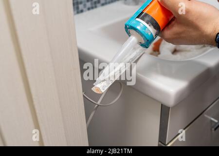 Plumber caulking bath tube with silicone glue using cartridge. Stock Photo
