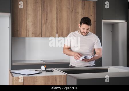 Argentinian man read instruction manual before installing kitchen furniture. Stock Photo
