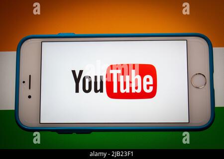 Kumamoto, JAPAN - Feb 22 2022 : The conceptual image of YouTube logo on an iPhone screen on the Indian national flag background in the dark mood. Stock Photo