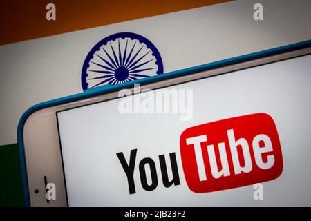 Kumamoto, JAPAN - Feb 22 2022 : The conceptual image of YouTube logo on an iPhone screen on the Indian national flag background in the dark mood. Stock Photo