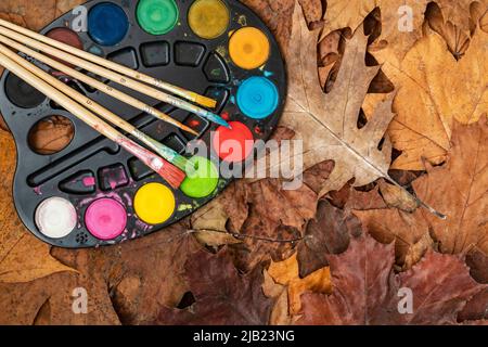 Watercolor paints on the autumn leaves. Concept of creativity. Autumn season still life. Fall time Stock Photo