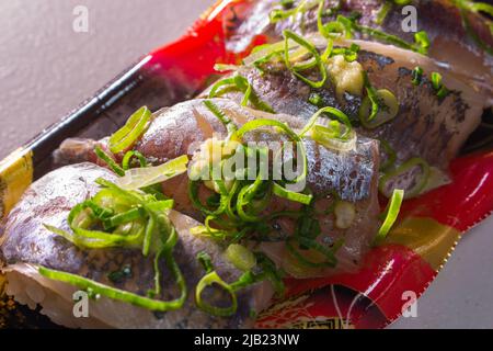 Horse Mackerel Sushi (Aji Sushi) with green onions & grated ginger packed in a food tray. Aji is the one of popular Sushi-neta in Edomae style Sushi Stock Photo
