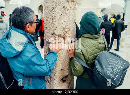 Bolgar, Tatarstan, Russia. May 21, 2022. Muslims touch the sacred pillar. The stone pillar around which the ritual circumambulation (Tawaf) is performed Stock Photo