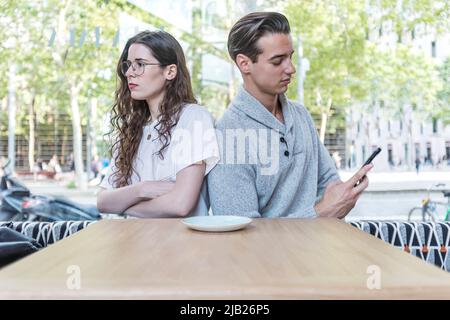 Young girl is feeling bored with her boyfriend because his addicted cellphone behavior ignoring her in relationship domestic problem. Social problem o Stock Photo