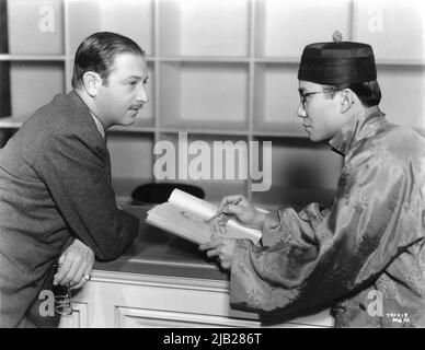 Director EDWIN L. MARIN being sketched by Chinese actor KEYE LUKE (in uncredited role as casino pageboy) on set candid during filming of THE CASINO MURDER CASE 1935 director EDWARD L. MARIN book by S.S. Van Dine Metro Goldwyn Mayer Stock Photo