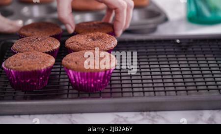 Step by step. Cooling red velvet cupcakes on a kitchen drying rack. Stock Photo