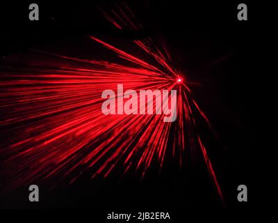 A bright spotlight projects red long beams in dark space. Laser show. Blurred image Stock Photo